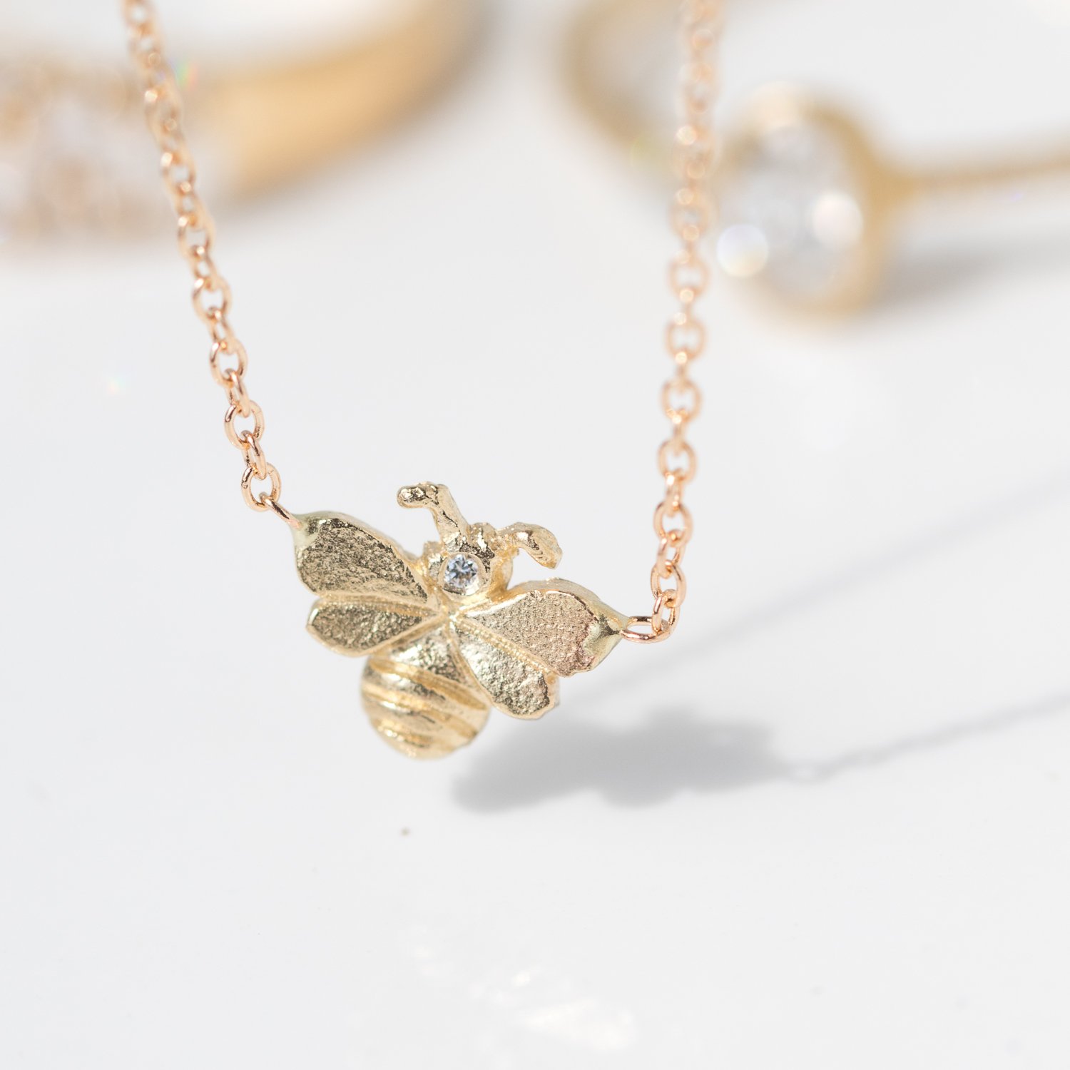 Tiny bee necklace in 14k yellow gold with diamonds