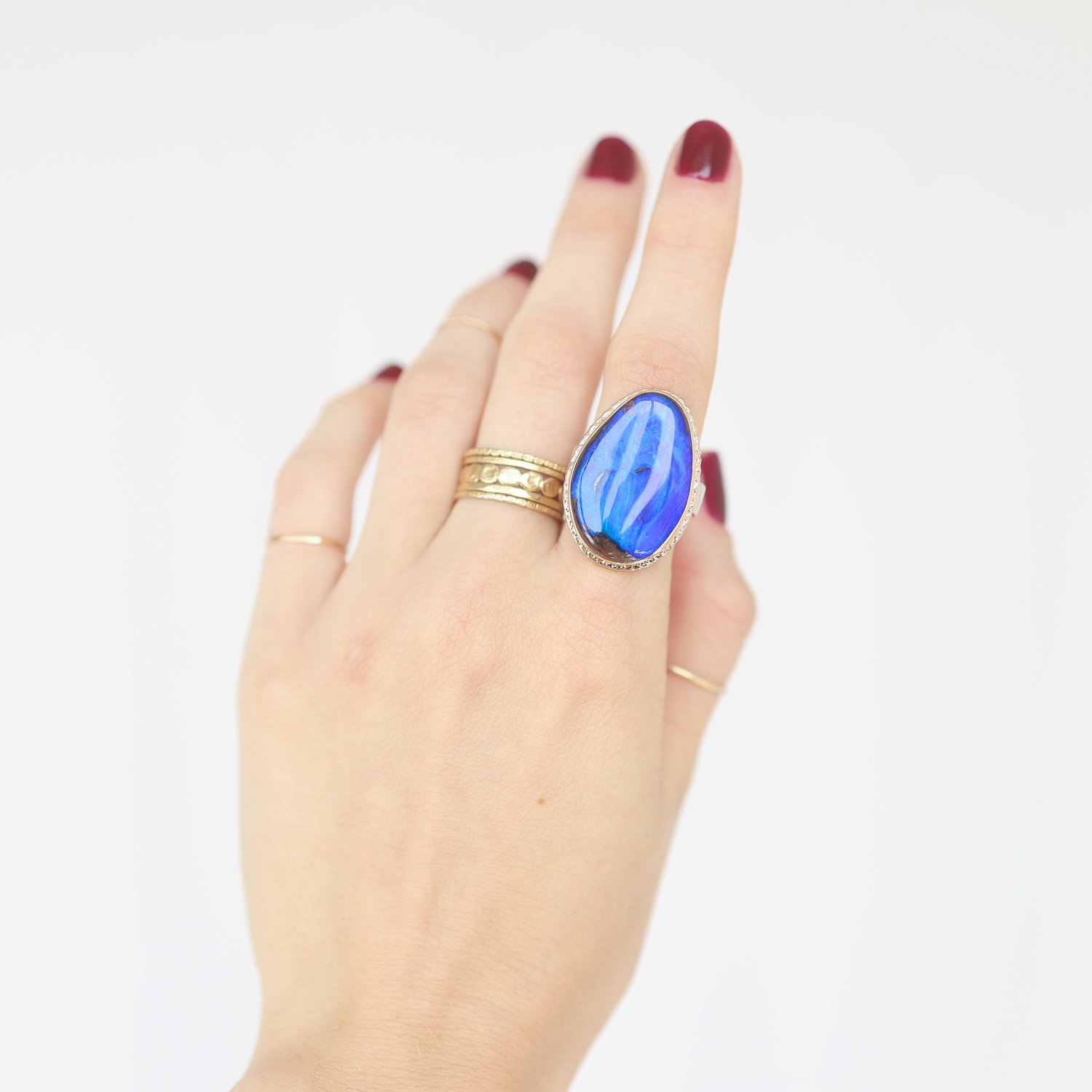 Jamie Joseph: Ring, Vertical asymmetrical, 14K gold bezel set Boulder opal on ruffled platform, Sterling silver wide eroded live edge band, Stone measures 1″ x 11/16″, Currently available in size 7 1/2