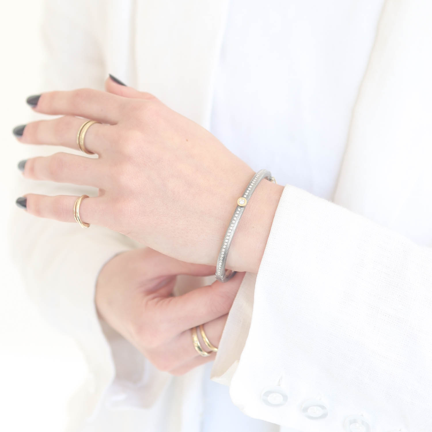 Rene Escobar Trunk Show:22 4MM. SS hinged bangle featuring an 18k YG push button style clasp and 18k YG bezel with RND cut 0.40ct of WH diamonds.