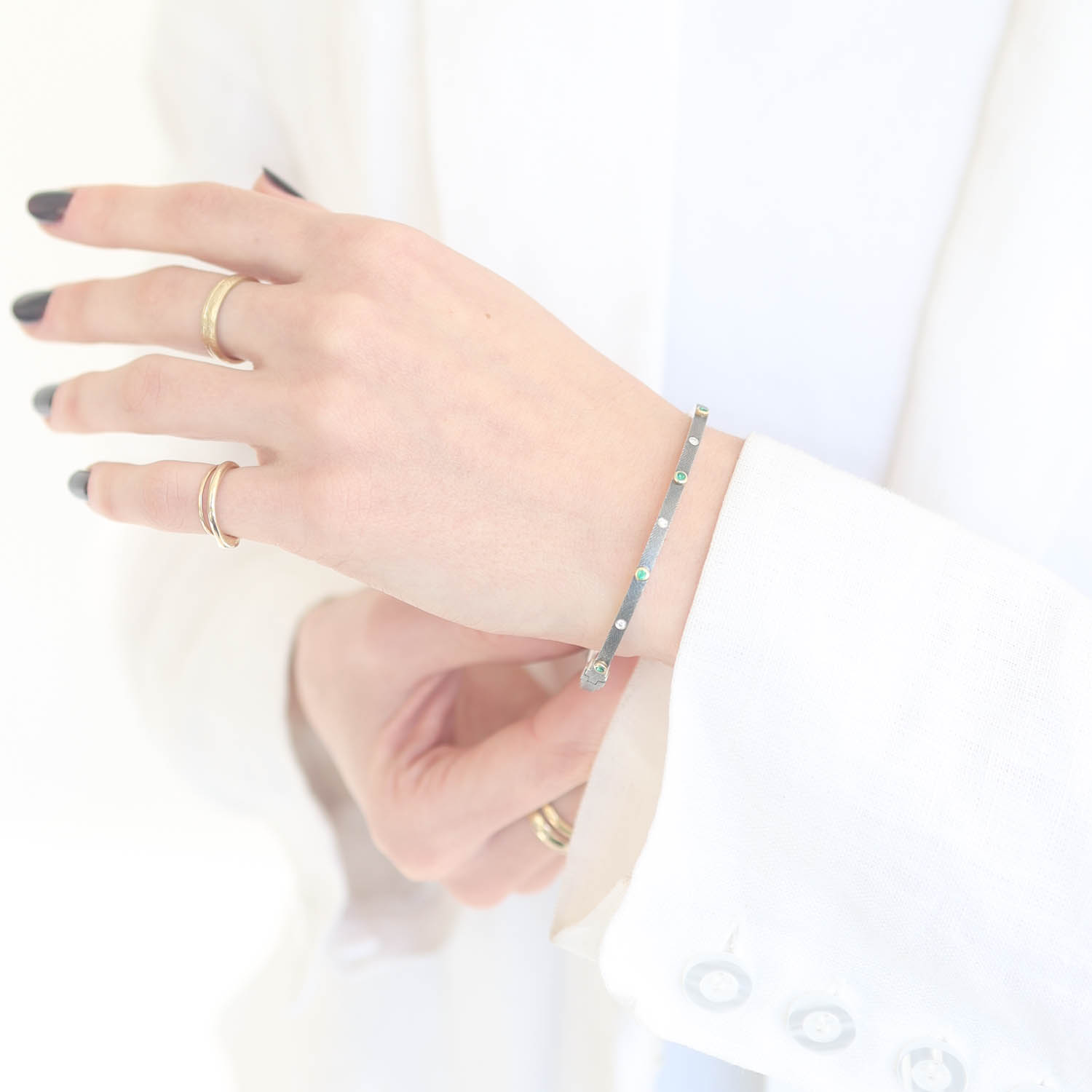 Rene Escobar Trunk Show:24 0.25CT 2.5MM. SS hinged bangle featuring an 18k YG push button style clasp and 5 18k YG bezels set with 0.25CT of EME.