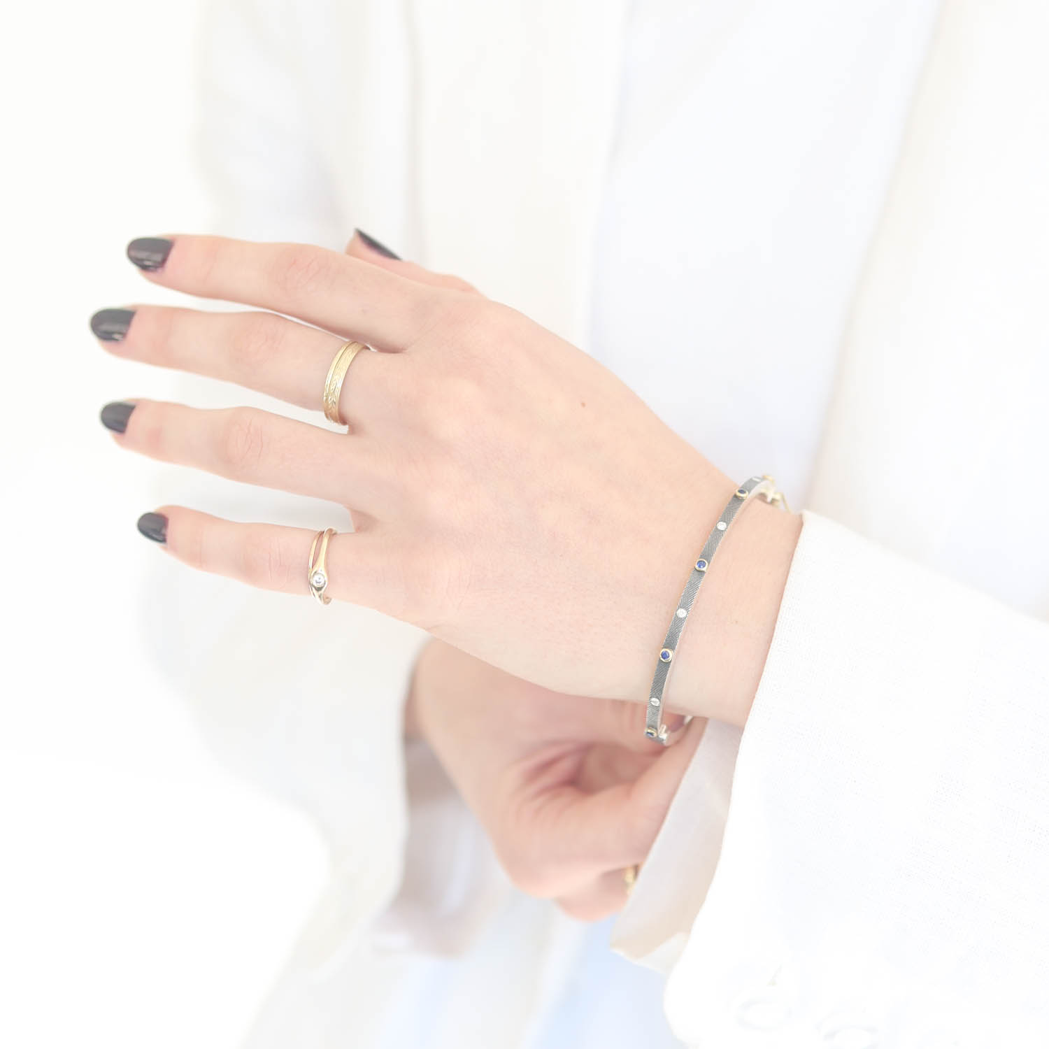 Rene Escobar Trunk Show:25 0.30CT 2.5MM. SS hinged bangle featuring an 18k YG push button style clasp and 5 18k YG bezels set with 0.30CT of SA.