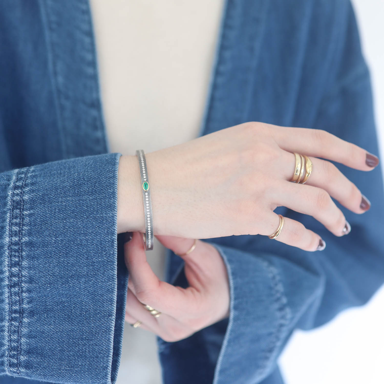 Rene Escobar:JUNIA PLUS 4MM SS hinged bangle featuring an 18k YG push button style clasp and a solid 18k YG top sheet and bezel set with OV cut with 0.48CT of EME